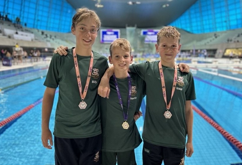 National Butterfly champion is pictured wearing his gold medal flanked by two fellow pupils who won silver at the London Aquatic Centre